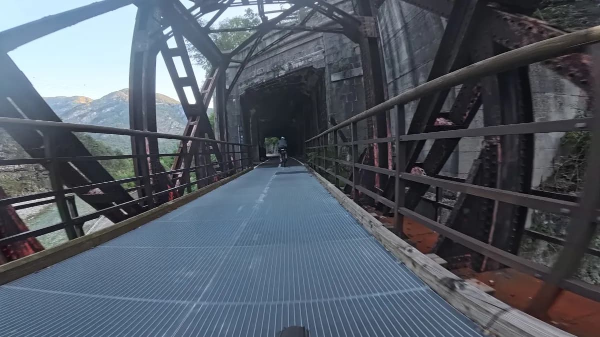 Eiserne Fachwerkbrücke mit Gitterrost, die direkt in einen Tunnel führt
