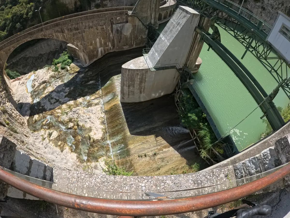 Steinerne Staumauer mit grünem Wasser in der Schlucht