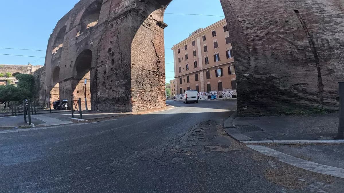 Hohe Backsteinbögen eines alten Aquädukts an einer Straße in Rom
