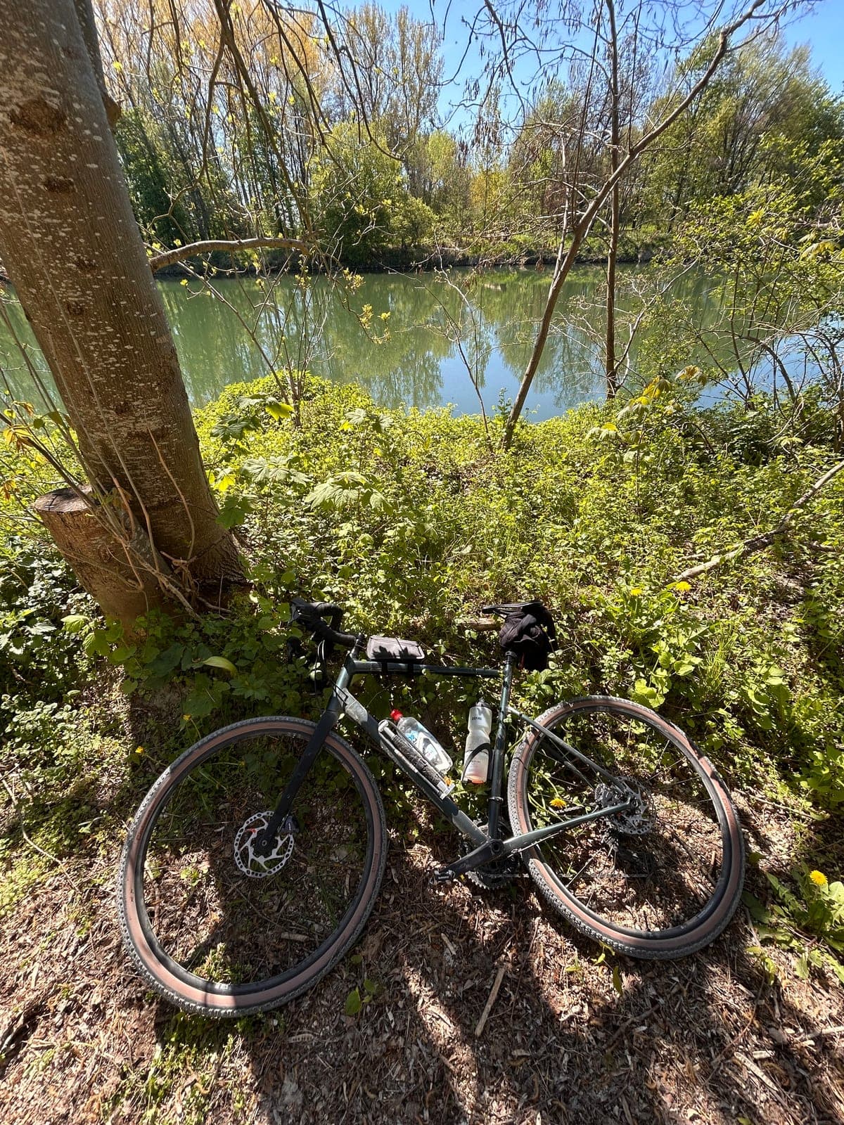 Gravelbike am Boden mit Donau im Hintergrund, Pause auf Tour 2025.