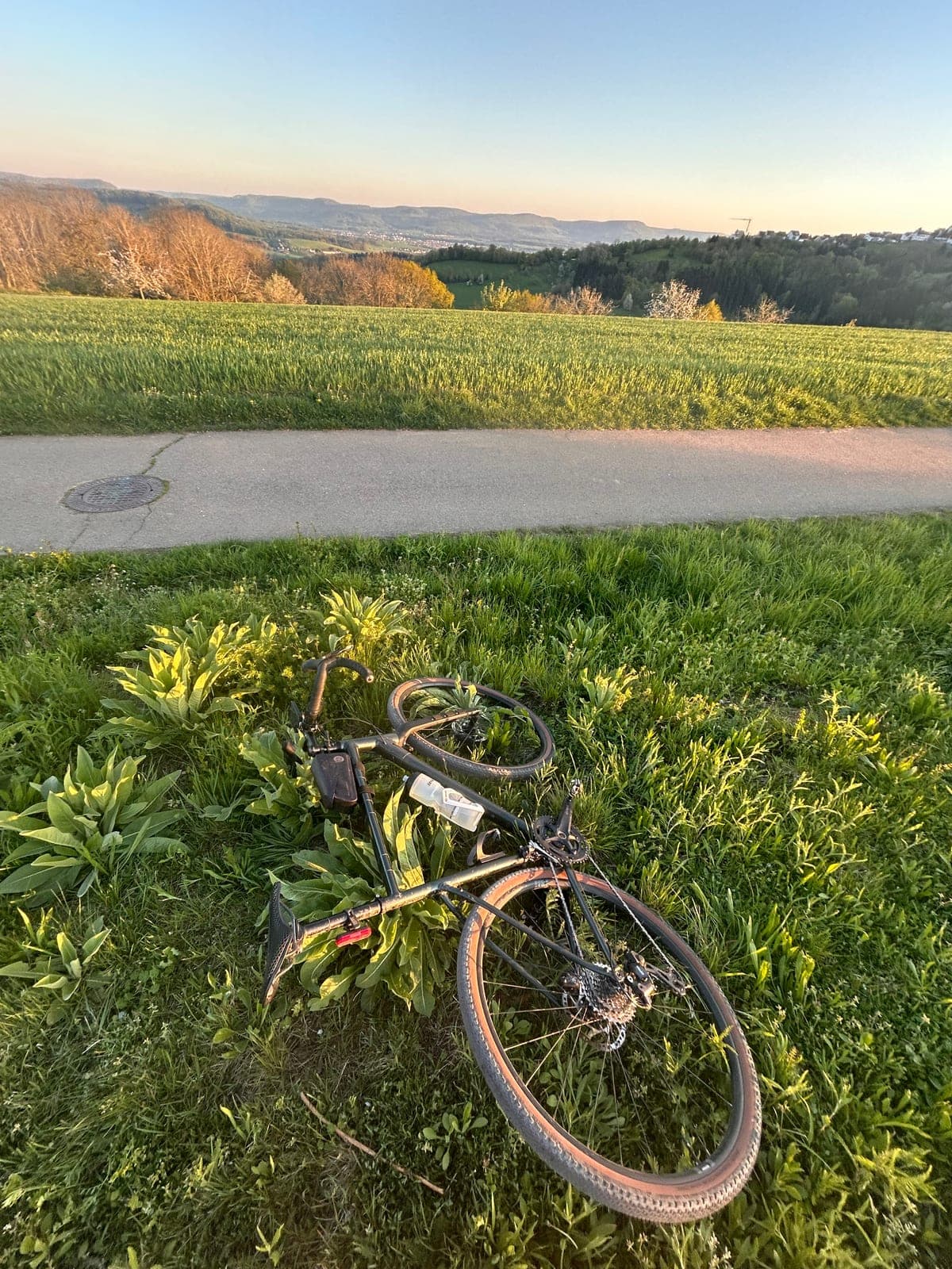 Gravelbike auf Feldweg mit Hügeln und gemischtem Himmel, 2025.