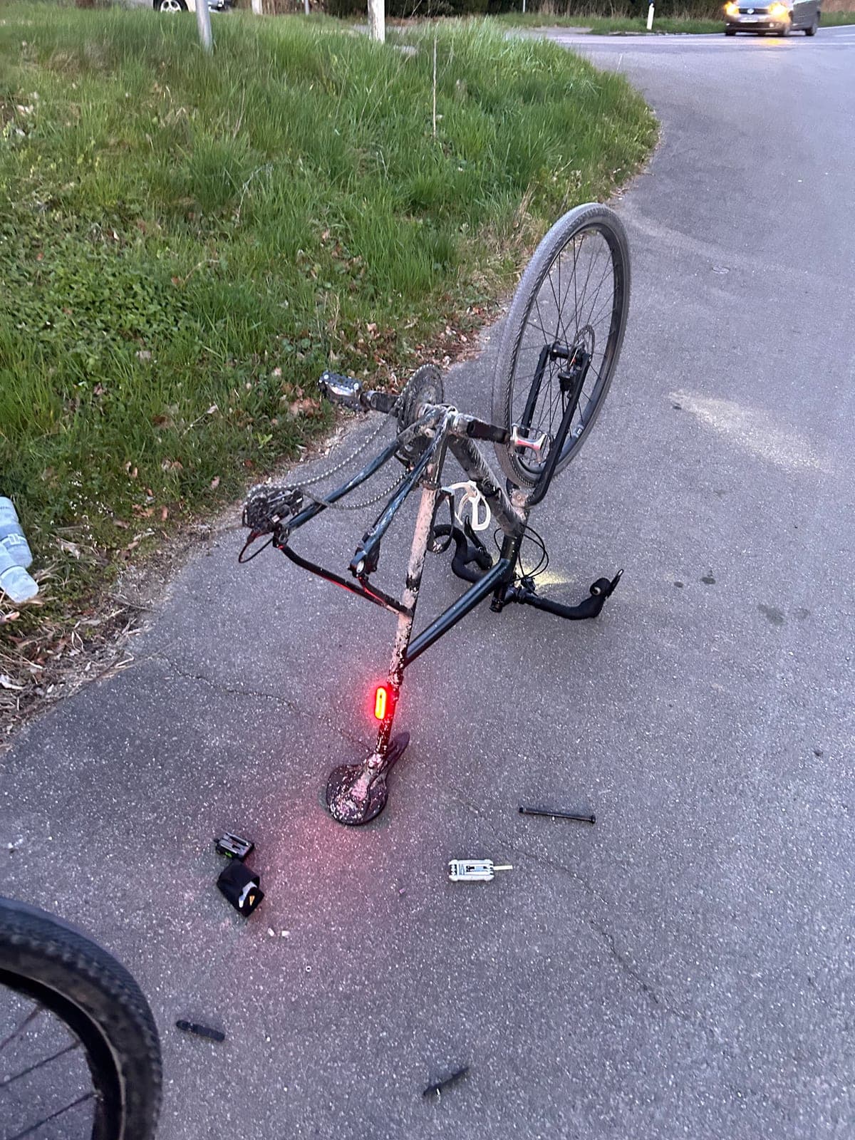 Gravelbike kopfüber am Straßenrand, Hinterrad ausgebaut, Multitool und Reifenheber auf dem Asphalt, 2025.